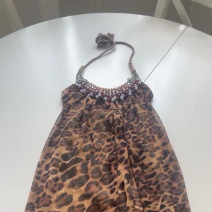 Leopardmönstrad axelväska med pärldetaljer - Säljer en unik klänning  med leopardmönster och snygga pärldetaljer vid öppningen.med träpärlor och är perfekt för dig som vill sticka ut. Materialet känns lätt och smidigt, och mönstret ger en cool vibe.