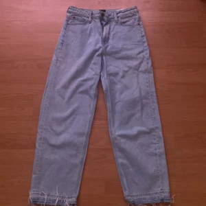 Ljusblå wide leg jeans från Lee - Säljer ett par ljusblå jeans från Lee med wide leg-modell och råa, fransiga benslut. Klassisk femficksdesign och normal passform i midjan. Perfekta för en avslappnad och trendig look.