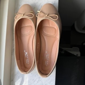 Beige ballerinaskor med rosett - Snygga beige ballerinaskor från Raglady med rund tå och dekorativ rosett framtill med guldfärgade detaljer. Skorna har platt sula och är gjorda i syntetmaterial, perfekta för en stilren och enkel look. Endast använda en gång, så som nya! 💓Skicka dm om ni har frågor eller funderingar !🥰köparen står för frakten ! 💓