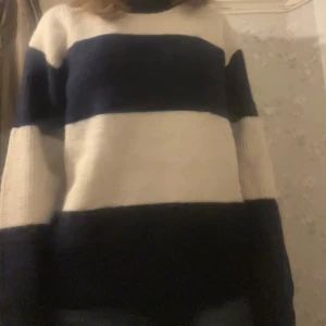 Randig stickad tröja från H&M - Säljer en stickad tröja från H&M i storlek L med breda marinblå och vita ränder. Tröjan har en klassisk rund halsringning och långa ärmar. Perfekt för dig som gillar en chill och avslappnad stil under höst och vinter.