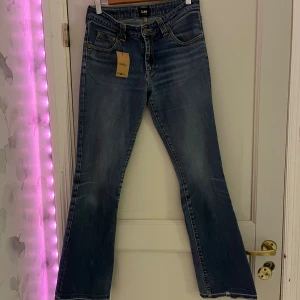 Blå bootcut jeans från Lee - Säljer ett par klassiska blå bootcut jeans från Lee med normal passform. Jeansen har fem fickor, dragkedja och knapp framtill samt snygga sömmdetaljer på bakfickorna. Perfekta till dig som gillar en tidlös denimlook. jag har storlek m och sitter perfekt på mig!