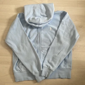 Ljusblå hoodie från Polo Ralph Lauren - Säljer en ljusblå hoodie från Polo Ralph Lauren. Original pris 2395 säljer för 1500 kr
