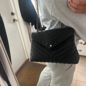 Svart axelväska - Säljer en svart quiltad axelväska med silverfärgade kedjeremmar och dekorativ nit framtill. Väskan är super fin och väldigt rymlig, perfekt när som helst! I ett superfint skick!!💖💞