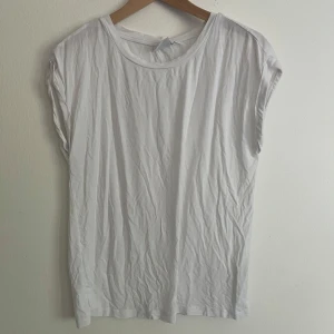 Vit t-shirt från Saint  - Enkel och stilren vit t-shirt från Saint i mjuk bomull. Modellen är ärmlös med rund halsringning och har en avslappnad bagie passform så snyggt att stoppa in i jeans osv♥️