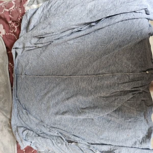 Grå långärmad kofta i bomull - En enkel och stilren grå kortärmad kofta i mjukt material. Perfekt att slänga på sig över en t-shirt för en chill och avslappnad look. Koftan har en rak passform och är lätt att matcha med det mesta.