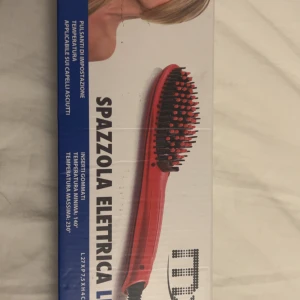 Röd elektrisk plattborste - En röd elektrisk plattborste med svarta och orange borst. Borsten har digital display och justerbar temperatur upp till 230°C. Perfekt för att snabbt och enkelt platta håret. Kommer med sladd och EU-kontakt.