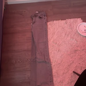 Grå bootcut jeans med hög midja - Säljer ett par grå jeans med bootcut-modell och hög midja. Jeansen har klassiska fem fickor, dragkedja och knapp framtill. Materialet är jeans och passformen är normal med utsvängda ben. Perfekta för en trendig och avslappnad look.