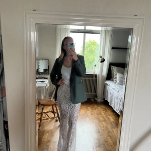 Vit lång spetskjol - Säljer en vit långkjol i spets med blommigt mönster. Kjolen är genomskinlig och har en elegant, figurnära passform. Perfekt för dig som vill ha en romantisk och trendig look. Kjolen är aldrig använd och har lappar kvar!