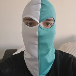 Grön/vit Hammarby balaclava/mask - Säljer en NY balaclava med tvåfärgad design, ena sidan grön och andra vit. Masken har öppningar för ögonen och är tillverkad i ett stretchigt syntetmaterial. Perfekt för kalla dagar eller aktiviteter utomhus.
