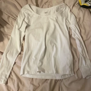 Vit långärmad topp från 157 - Enkel och stilren vit långärmad topp från 157 med rundad halsringning. Tillverkad i mjuk bomull, perfekt för lager-på-lager eller som basplagg. Passformen är normal och materialet känns skönt mot huden.