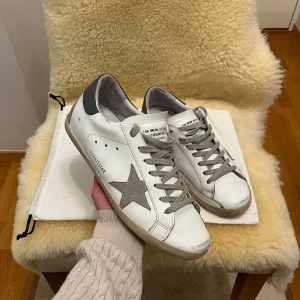 Golden Goose Skor - Sjukt feta Golden Goose Superstar skor som är perfekta för de kommande sommarkvällarna✨Storlek: 44✨Skick: Bra skick, liten ”skavank” på höger häl (se bild 5)✨Färg: Vit och grå✨Var inte rädd att ställa frågor om pris, bilder etc🤗Endast dustbag ingår, ej OG box eller annat