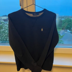 Ralph Lauren sweatshirt - Klassisk mörkblå sweatshirt från Polo Ralph Lauren med rund halsringning och broderad vit logga på bröstet. Tröjan har ribbade muddar och är tillverkad i mjuk bomullsmix. Perfekt för en chill och stilren look. 