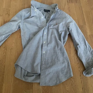 Ljusblå oxfordskjorta från Polo Ralph Lauren🙌 - Klassisk ljusblå oxfordskjorta från Polo Ralph Lauren i slim fit. Skjortan har långa ärmar, knappar framtill och den ikoniska broderade loggan på bröstet. Perfekt till både jeans och chinos.