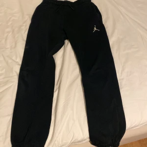 Svarta mjukisbyxor från Jordan - Svarta mjukisbyxor från Jordan med klassisk logga på ena benet. Byxorna har resår i midjan med snörning och muddar vid bensluten. Perfekta för chill eller träning.