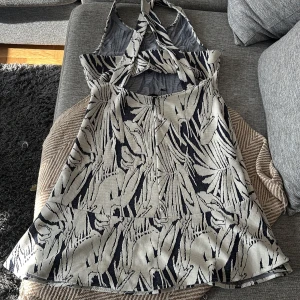 Mönstrad kortklänning från Mango - Supersnygg kortklänning från Mango med (blå/svart) och beige mönster. Klänningen har ärmlös design, rund hals och volang nertill. Materialet känns lite tjockare och strukturerat, perfekt för att sticka ut med ett coolt print. Så himla fin står L och är oanvänd men jag tycker M. 