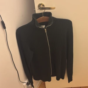 Svart ziptröja - En svart zip tröja i ett varmt material från jack n jones. Perfekt att ha över skjortan eller bara en t-shirt. Den är knappt använd utan har bara hängt i garderoben. Kom privat för ytterligare frågor!