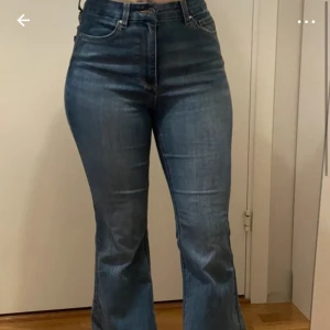 Blå bootcut jeans - Snygga blå bootcut jeans med hög midja. De har en klassisk femficksdesign och en knappgylf. Perfekta för en avslappnad stil. I storlek s/30