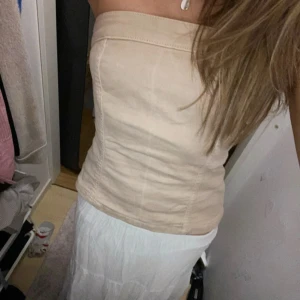 Beige tubtopp - Säljer en stilren beige tubtopp. Perfekt för varma dagar eller som en del av en lager-på-lager-look. Toppen har en enkel och elegant design som passar till många olika outfits.❣️
