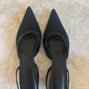 Svarta spetsiga pumps från NA-KD - Snygga svarta pumps från NA-KD med spetsig tå och glittrig yta. Perfekta för en kväll ute eller en speciell tillställning. De är helt oanvända!!!!✨✨✨🥂