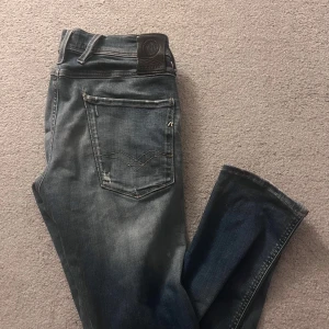 Replay ambass  - Snygga blå jeans från Replay med slitna detaljer och en cool tvätt. De har en klassisk femficksdesign och knappgylf. Perfekta för en avslappnad stil.