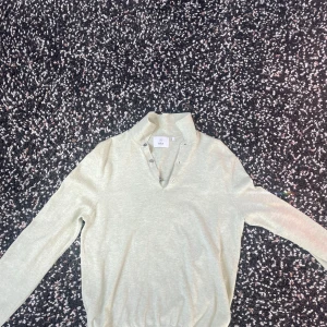 Beige tröja från Bläck - Säljer en stilren beige tröja från Bläck med knappar vid halsen. Tröjan har långa ärmar och en mjuk känsla, perfekt för en avslappnad look. Passar bra till både jeans och chinos.