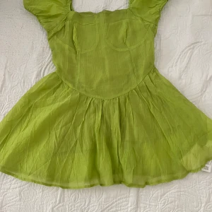 Grön klänning med puffärmar - Säljer en söt grön klänning med puffärmar och en luftig kjol. Klänningen har en smickrande passform och är perfekt för varma dagar. Den är tillverkad i ett lätt material som ger en skön känsla.