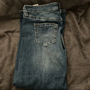 Blå baggy jeans från True religion  - Säljer ett par blå baggy jeans från True religion. De har en avslappnad passform och klassisk femficksdesign. Perfekta för en casual look.