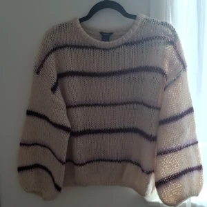 Beige stickad tröja från Lindex - Mysig beige stickad tröja från Lindex med lila ränder. Tröjan är använd 2/3 gånger är i väldigt bra skick!
