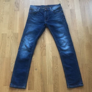 Blå jeans från Nudie Jeans - Snygga blå jeans från Nudie Jeans med en klassisk femficksdesign. De har en slim passform och är tillverkade i slitstarkt denim. Perfekta för en avslappnad stil. Använt 1-3 gånger. 