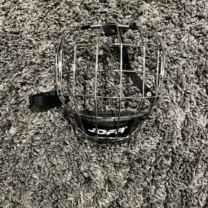 Jofa ansiktsgaller för hjälm - Säljer ett Jofa ansiktsgaller i storlek L, perfekt för hockeyhjälmar. Gallret är i metall och har justerbara remmar för säker passform. Tillverkat i Sverige och CE-märkt för säkerhet.