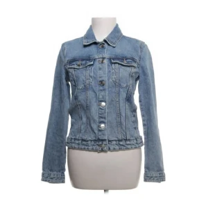 Ljusblå jeansjacka - Snygg ljusblå jeansjacka med klassisk design och knappar framtill. Jackan har långa ärmar och två bröstfickor med knappstängning. Perfekt för en avslappnad stil.