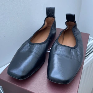 Svarta ballerinaskor från ATP Atelier - Snygga svarta ballerinaskor från ATP Atelier i mjukt skinn. De har en unik fyrkantig tå och en stilren design som passar perfekt för en elegant look. Skorna har en diskret dragflik baktill för enkel påtagning.