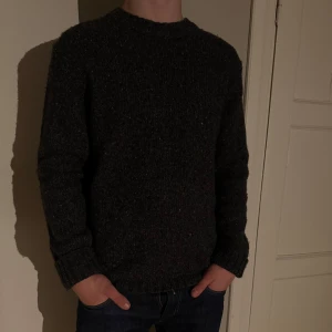 Stickad tröja från Paul & friends - Stickad grå/svart tröja från Paul & friends stickad i 62% merinoull och 8% alpaca. Tröjan är köpt i deras butik på NK för 2199kr. Modellen är 183cm.