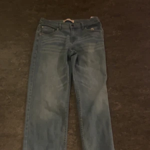 Blå jeansbyxor från Levis - Säljer ett par klassiska blå jeansbyxor från Levis. De har en rak passform med fem fickor och en knappgylf. Perfekta för en avslappnad stil.