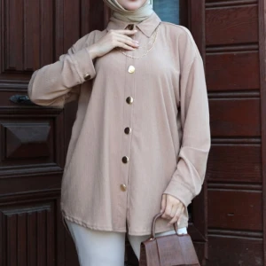 Beige skjorta med knappar - Snygg beige skjorta med stora knappar framtill. Skjortan har en klassisk krage och långa ärmar, perfekt för en stilren look. Passar bra till både vardag och mer uppklädda tillfällen.