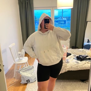 Vit hoodie med huva och snörning - Säljer en vit hoodie med huva och snörning. Tröjan har en klassisk känguruficka framtill och en relaxed, lite oversized passform. Perfekt för chill dagar eller när du vill ha något bekvämt och enkelt. Lite nopprig 