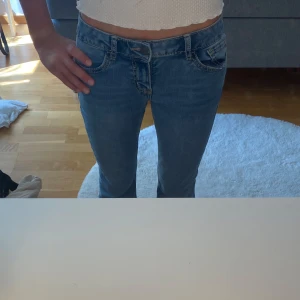 Blå bootcut jeans från Lindex - Snygga blå bootcut jeans från Lindex med coola bakfickor som har stjärnbroderi och kontrastsömmar❣️Klassisk femficksmodell i stretchig denim med normal passform och medelhög midja😇.