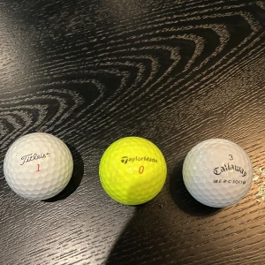 Golfbollar: Titleist Pro V1x, TaylorMade, Callaway ERC Soft - Tre golfbollar från kända märken: en vit Titleist Pro V1x, en gul TaylorMade och en vit Callaway ERC Soft. Perfekt för dig som vill sticka ut på golfbanan och testa olika bollar för bästa spelupplevelse.