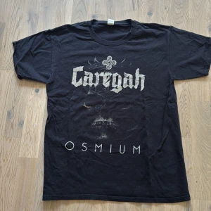 Svart Caregah band-tshirt Fruit of the Loom - Svart t-shirt från Fruit of the Loom med tryck av bandet Caregah och texten 'Osmium' på framsidan. Klassisk passform, rund hals och korta ärmar. Tillverkad i mjuk bomull, perfekt för dig som gillar bandmerch och vill sticka ut.