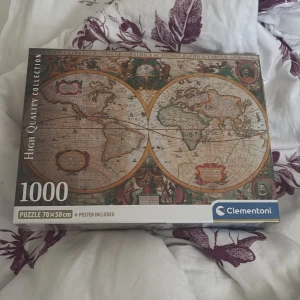 High Quality Collection: 1000 Puzzle (Världskarta) - Upptäck världen bit för bit med detta 1000-bitars pussel från Clementoni! Motivet är en klassisk världskarta, perfekt för dig som gillar utmaningar och snygg inredning. Pusslet är 70x50 cm och inkluderar en poster. Perfekt för unga vuxna och äventyrslystna.