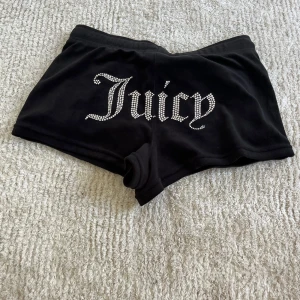 Svarta Juicy Couture shorts  - Svarta shorts från Juicy Couture i mjuk velour med glittrande stenar som bildar texten 'Juicy' på baksidan. Använda två gånger. Storlek M