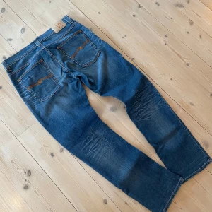 Nudie jeans Grim Tim 34/32 - Säljer ett par feta nudie jeans i den populäraste modellen ”Grim Tim”! Jeansen har en sjukt fet tvätt och en perfekt färg som passar året runt!🙌🏻 Skriv vid funderingar!!!⚜️⚜️⚜️