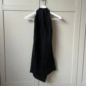 Grå/Svart klänning med knyt bak - Svart, kort klänning med öppen rygg. Klänningen är ärmlös. 