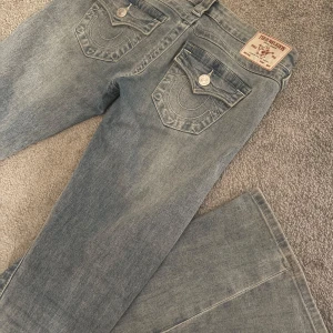 True Religion Joey bootcut jeans blå - Säljer ett par ljusblå True Religion Joey jeans med bootcut (säljs för jag har två par). Har använt dessa någon enstaka gång. Snygga detaljer med kontrastsömmar, silverfärgade knappar och ikoniska bakfickor med lock. Låg midja och passar perfekt för mig som är ca 166 cm lång! 💕