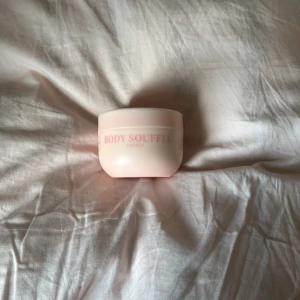 Gunry Body Soufflé Energy - Body Soufflé Energy från Gunry i en ljusrosa rund plastburk med rosa text. Vegansk formula och doften Core Crush. Perfekt för dig som vill ha en återfuktande och lätt kroppskräm med fräsch känsla.