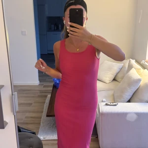 Rosa ribbad långklänning - Säljer en snygg rosa långklänning med ribbad struktur. Klänningen är ärmlös med rund halsringning och har en slits nertill på ena sidan. Perfekt för dig som gillar en enkel men stilren look.