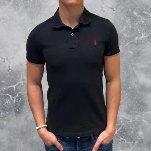 Ralph Lauren Piké svart | Slim-Fit - •Ralph Lauren Piké Svart. Skick: 8/10, Inga skador! Storlek: 14/16 år slim-fit = XS~. Modell: 173 cm, 65 kg. Sitter bra på modellen på bild! Authentic: ✅. Hör av dig vid frågor eller funderingar, mvh Hessler’s;)