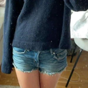 Blå jeansshorts med fransig kant - Snygga blå jeansshorts med låg midja och rå, fransig kant nertill. 