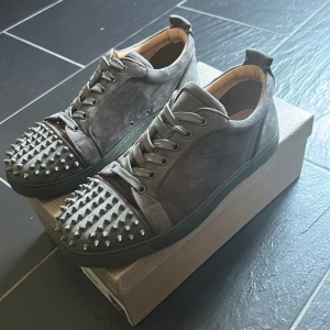 Gråa Christian Louboutin sneakers med nitar - Säljer dessa feta skor från Louboutin med nitar perfekt för dig som vill sticka ut lite. Kan gå ner i pris lite vid snabb affär. Skriv gärna om ni har några frågor🤗‼️1:1‼️