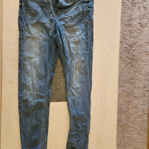 Blå jeans från H&M, midwaist 33/32 - Klassiska blå jeans från H&M i midwaist-modell. Jeansen har fem fickor, dragkedjegylf och raka ben. Tillverkade i bomullsdenim med snyggt tvättad look och diskreta slitningar. Perfekta för en avslappnad och stilren vardagsstil.